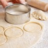Wykrawacz do pierogów w użyciu – wycinanie okrągłych placków z ciasta na drewnianym blacie