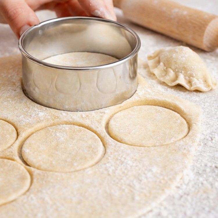 Wykrawacz do pierogów w użyciu – wycinanie okrągłych placków z ciasta na drewnianym blacie