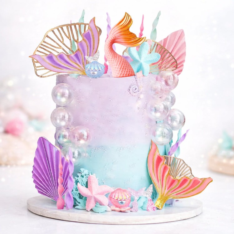 Tort tematyczny syrenka ozdobiony ogonami syrenek, muszelkami, rozgwiazdami i pastelowymi dekoracjami