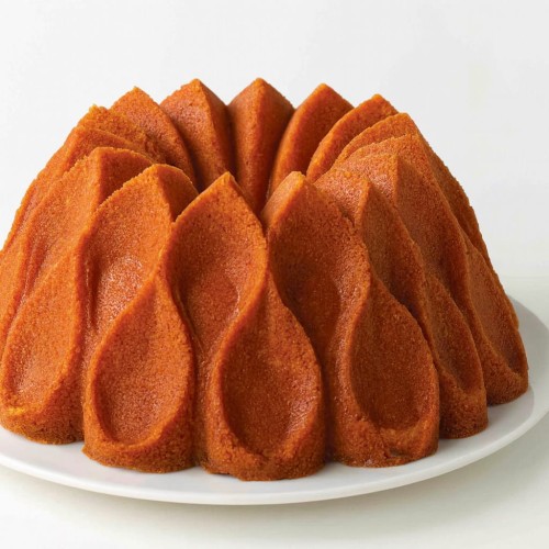 Upieczona babka wielkanocna o złocistym kolorze z dekoracyjnym, rzeźbionym wzorem na białym talerzu