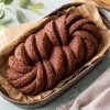 Upieczone ciasto o plecionym, skręcanym wzorze w prostokątnej formie wyłożonej papierem do pieczenia