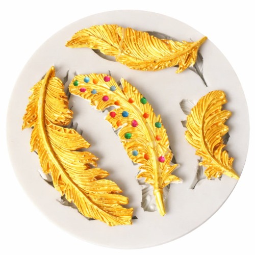 Silikonowa forma z czterema piórami w kolorze złota ze złotej masy dekoracyjnej, w tym jedno ozdobione kolorowymi akcentami.