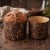 Czekoladowa babka panettone w ozdobnej papierowej formie ze złotymi ornamentami obok pustej formy