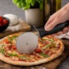 Nóż do krojenia pizzy Patisse przecina świeżo upieczoną pizzę na desce.