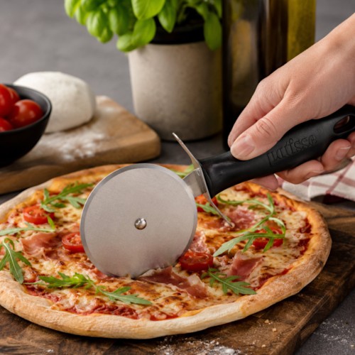 Nóż do krojenia pizzy Patisse przecina świeżo upieczoną pizzę na desce.