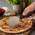 Nóż do krojenia pizzy Patisse przecina świeżo upieczoną pizzę na desce.