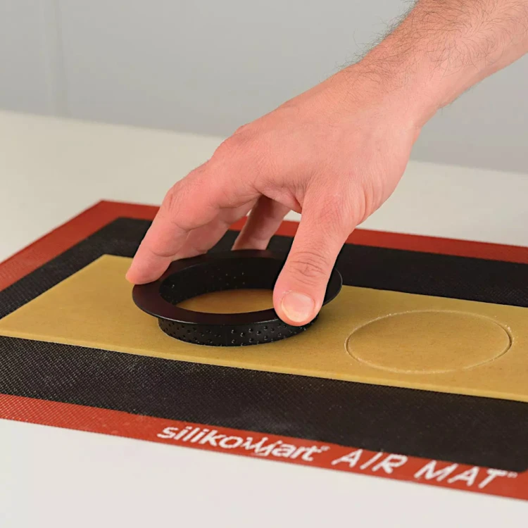 Ręka układająca perforowany ring na cieście położonym na silikonowej macie Silikomart Air Mat.