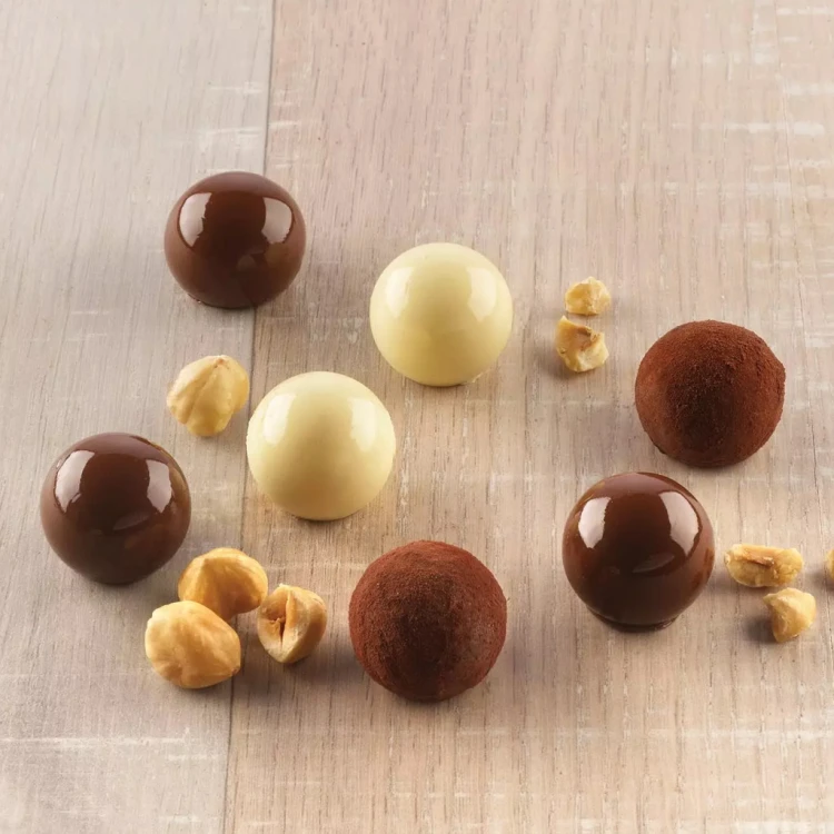 Okrągłe czekoladki w trzech wariantach — ciemne, białe i obtoczone w kakao — ułożone na drewnianym blacie.