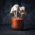 Halloweenowy cakepops w kształcie duszka, ustawiony w szklance z pomarańczową posypką.