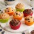 Gotowe muffinki w kolorowych papilotkach Patisse, ułożone na białej podstawie wraz z dodatkami do dekoracji.