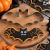 Foremka nietoperz z ciasteczkiem udekorowanym czarnym lukrem w halloweenowej scenerii - idealna do tematycznych wypieków.