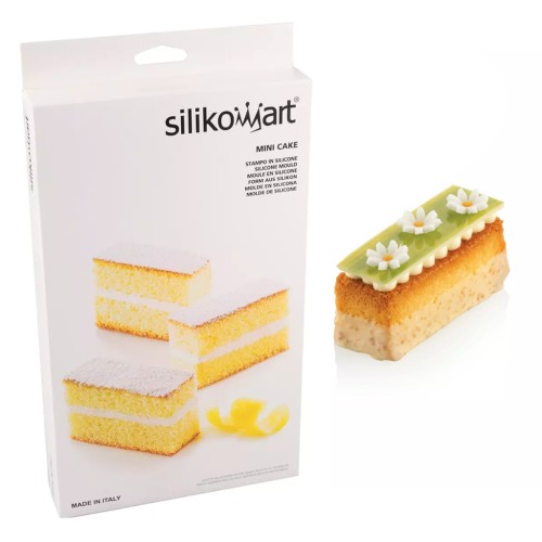 Forma Silikomart Mini Cake w opakowaniu obok gotowej monoporcji w kształcie prostokąta, ozdobionej zieloną dekoracją i białymi kwiatkami.