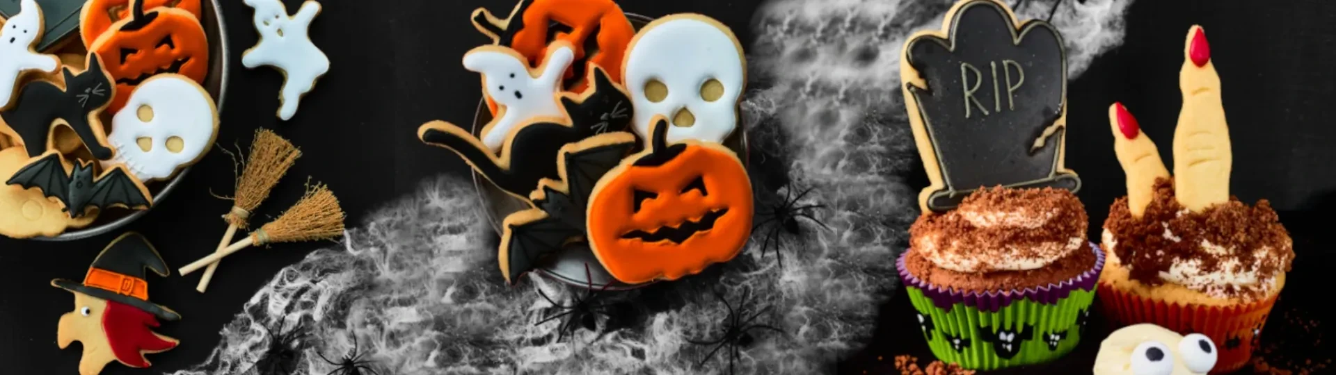 Ciasteczka na Halloween wykrojone metalowymi foremkami do ciastek i pierników. Ozdobione białym i pomarańczowym lukrem. Obraz na czarnym tle z pajęczyną.